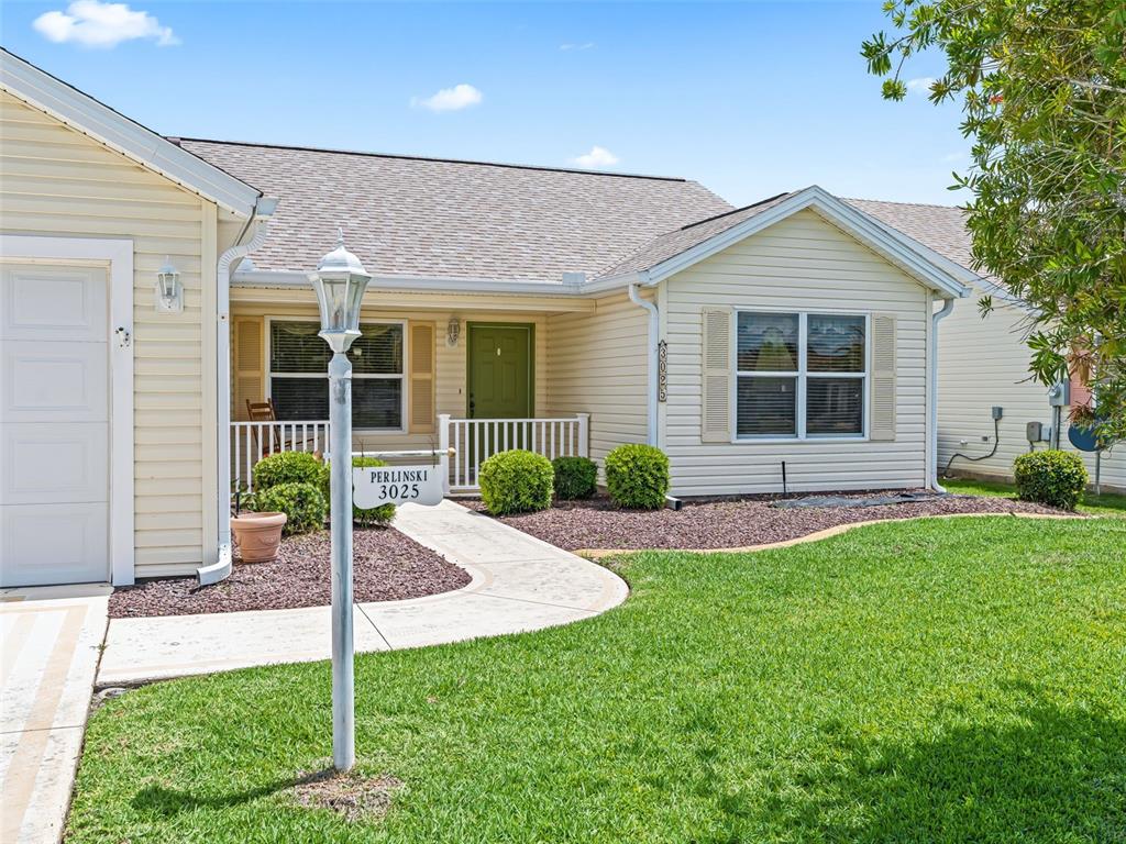 A single-story house with light yellow siding, a green front door, and a lamp post — 3025 HOBART COURT, THE VILLAGES, FL