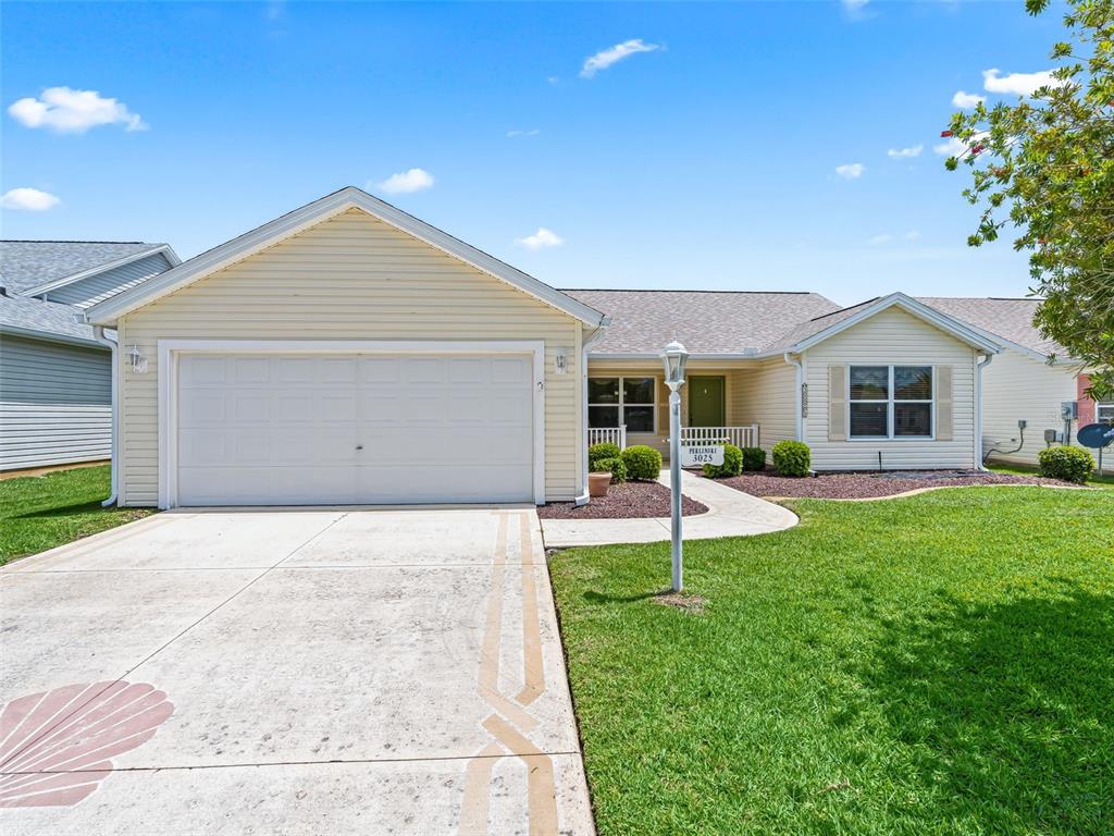 A single-story house with light yellow siding, a two-car garage, and a concrete driveway — 3025 HOBART COURT, THE VILLAGES, FL