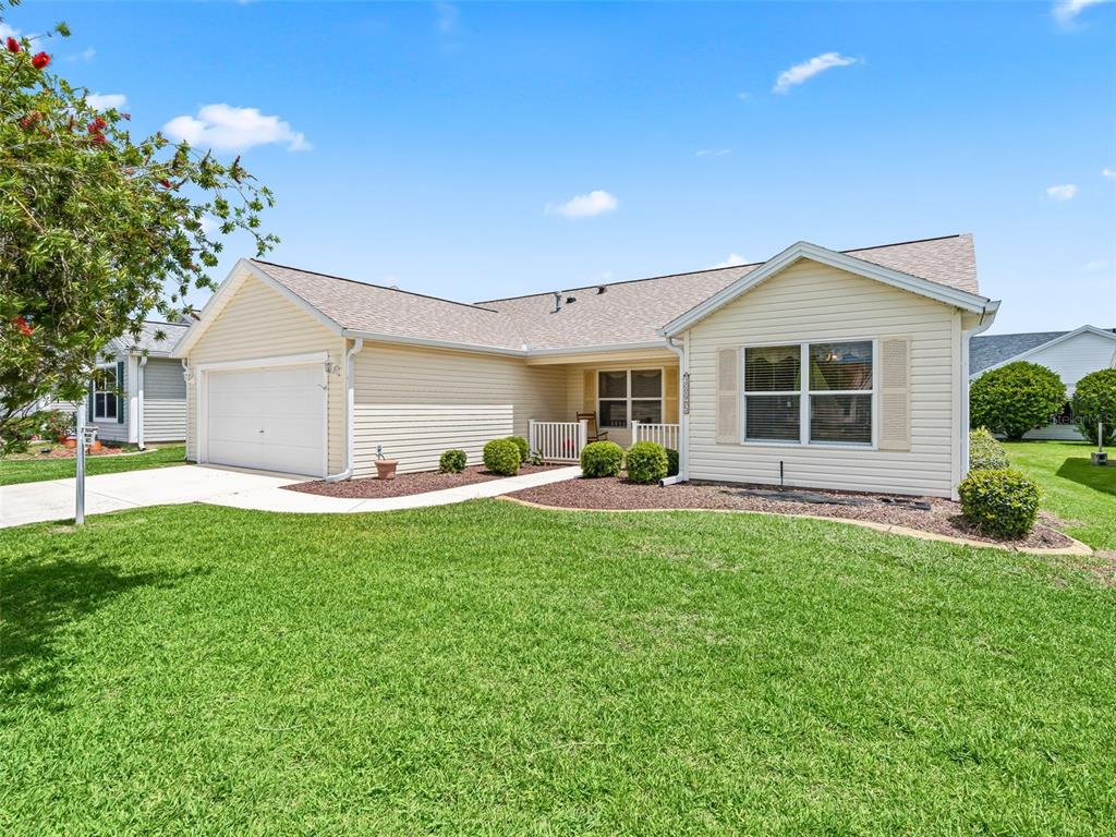 A single-story house with light yellow siding, a two-car garage, and a front porch — 3025 HOBART COURT, THE VILLAGES, FL