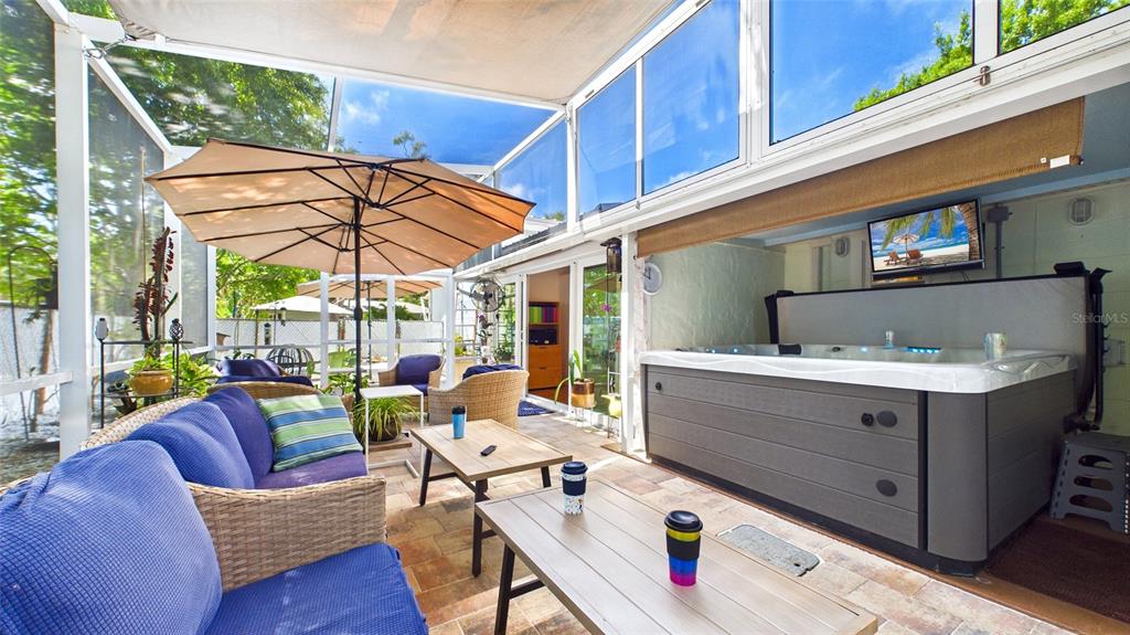 A screened-in patio features a hot tub, outdoor furniture, and a television under a roof — 5005 24TH AVENUE S, GULFPORT, FL