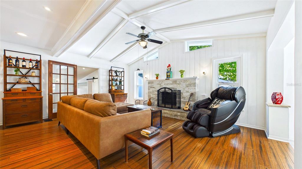 A living room features a stone fireplace, vaulted ceiling, wood flooring, and a massage chair — 5005 24TH AVENUE S, GULFPORT, FL