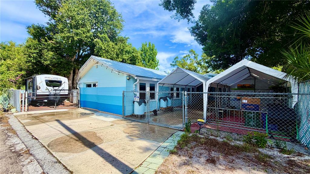 A light blue house with a metal roof sits next to a fenced-in carport area — 5005 24TH AVENUE S, GULFPORT, FL