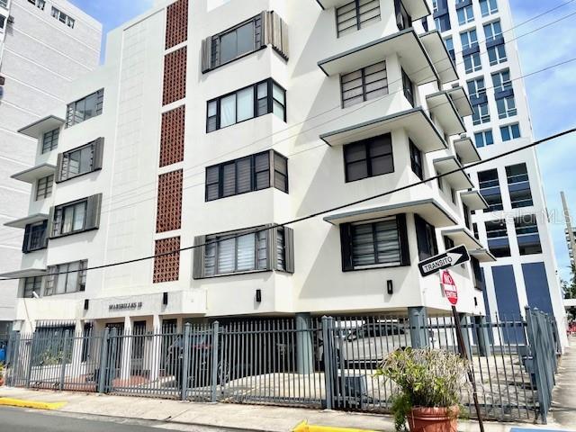 A multi-story white apartment building features a ground-level parking area behind a metal fence — 18 MARSEILLES UNIT 4B, SAN JUAN, PR