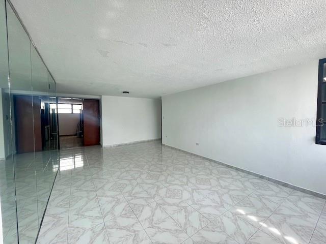 An empty room features white walls, a textured ceiling, and light-colored patterned tile flooring — 18 MARSEILLES UNIT 4B, SAN JUAN, PR