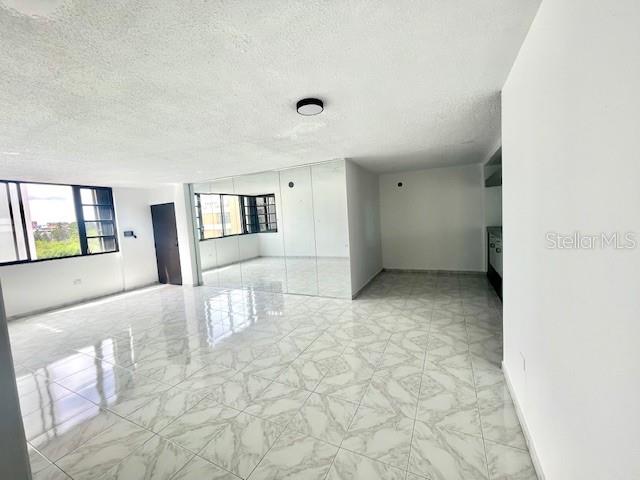 An open-concept room features white tiled floors, mirrored walls, and a large window — 18 MARSEILLES UNIT 4B, SAN JUAN, PR