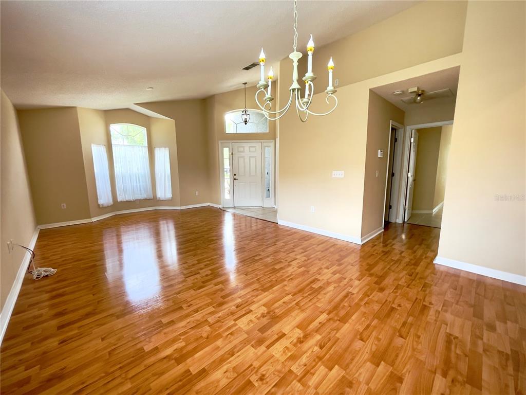 A living room with hardwood floors, a chandelier, and a front entryway with a door — 834 SENECA MEADOWS ROAD, WINTER SPRINGS, FL