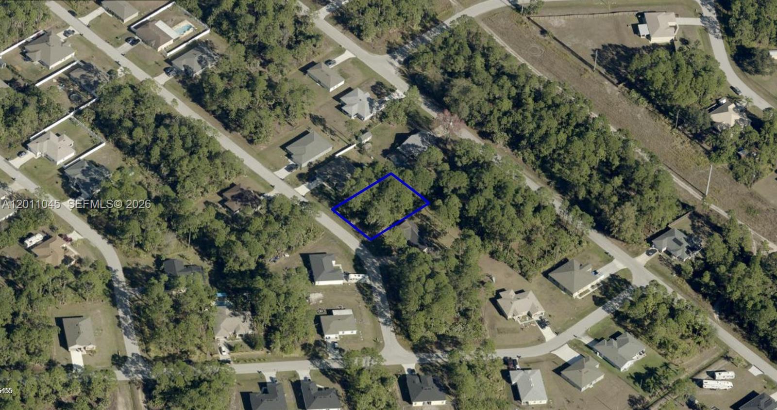 An aerial view shows a vacant, wooded residential lot outlined in blue on a street — 1171 SW GAWAIN RD, Palm Bay FL 32908, PALM BAY, FL