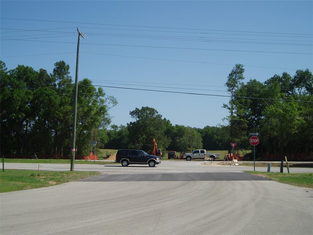 A black SUV drives across a paved intersection near construction equipment and a stop sign — TBD HIGHWAY 441, ALACHUA, FL