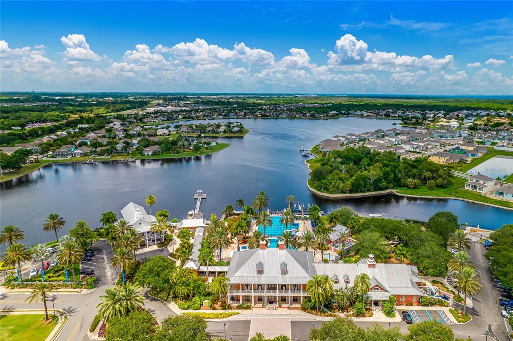An aerial view shows a large clubhouse with a pool beside a lake and neighborhood — 325 SHORE CRAB WAY, APOLLO BEACH, FL