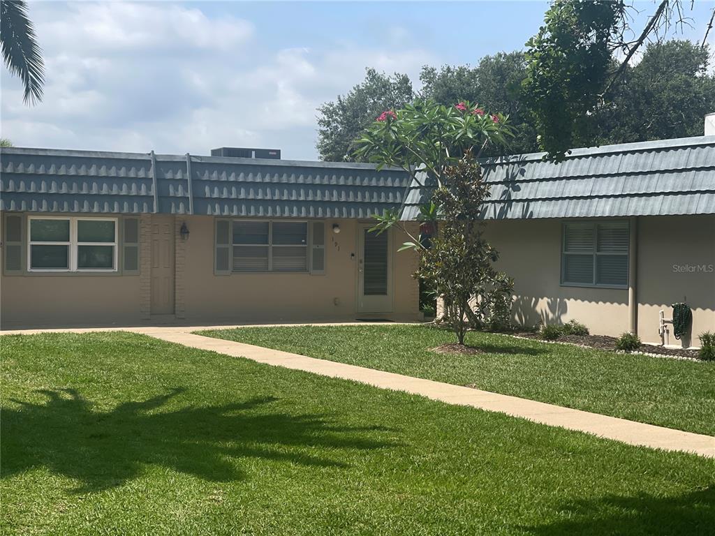 A single-story house with a tan exterior, gray roof tiles, and a front walkway — 1802 BEDFORD TERRACE UNIT 191, SUN CITY CENTER, FL