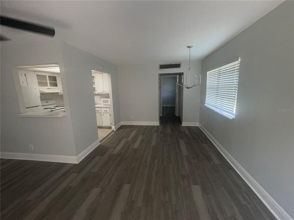 A dining area with gray wood-look flooring, light gray walls, and a chandelier — 1802 BEDFORD TERRACE UNIT 191, SUN CITY CENTER, FL