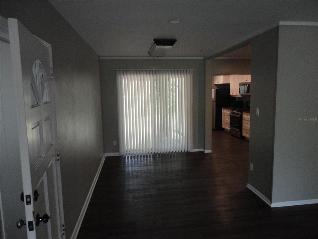 A living area with dark wood floors leads to a kitchen and sliding glass doors — 401 NW 36TH TERRACE, GAINESVILLE, FL