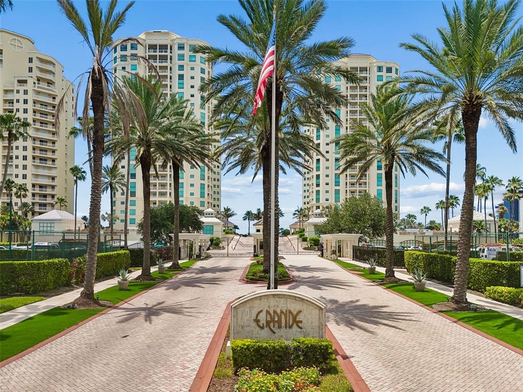 A paved driveway leads to the gated entrance of a residential complex with tall buildings — 1170 GULF BOULEVARD UNIT 403, CLEARWATER BEACH, FL