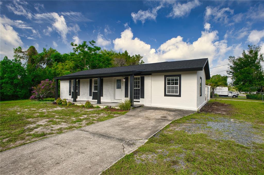 A white single-story house with a black roof and shutters features a front porch — 102 AMIGOS ROAD, DEBARY, FL