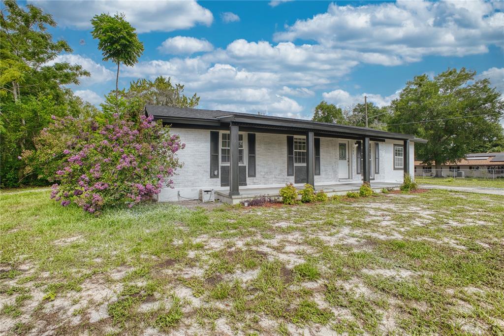 A single-story white brick house features a covered front porch and black window shutters — 102 AMIGOS ROAD, DEBARY, FL