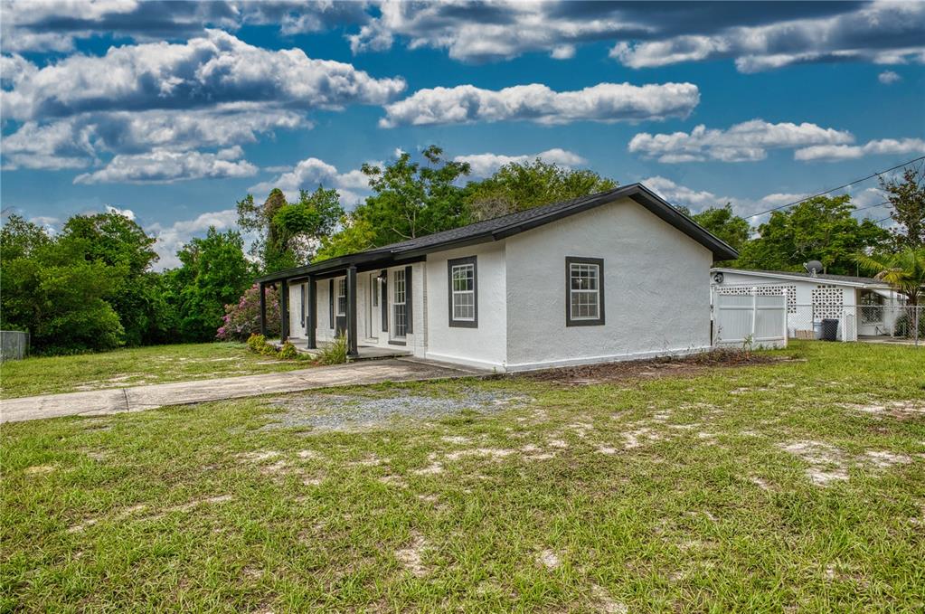 A white, single-story house with a covered front porch sits on a grassy lot — 102 AMIGOS ROAD, DEBARY, FL