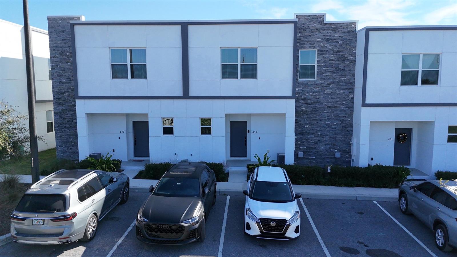 An exterior view of a modern two-story townhouse complex with a parking lot in front — 653 Trikomo Drive, Davenport FL 33896, DAVENPORT, FL