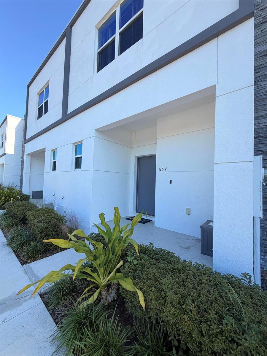A modern two-story townhouse exterior features a grey front door and a small entryway — 653 Trikomo Drive, Davenport FL 33896, DAVENPORT, FL