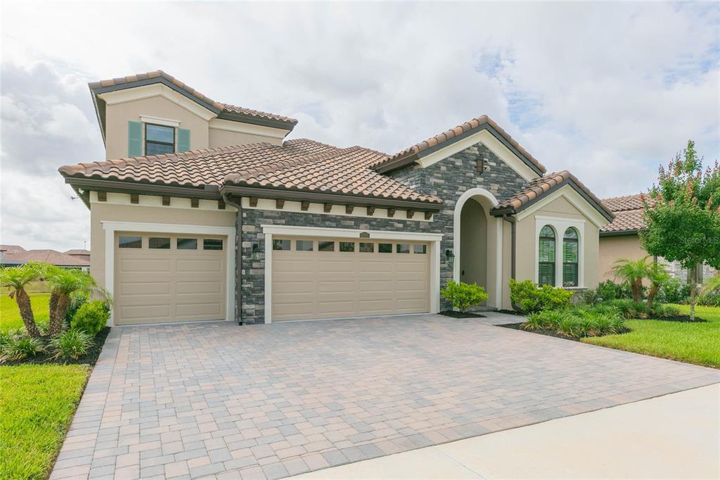 A two-story house with a stone facade, tile roof, and a three-car garage — 11105 RUSTIC TIMBER LOOP, SAN ANTONIO, FL