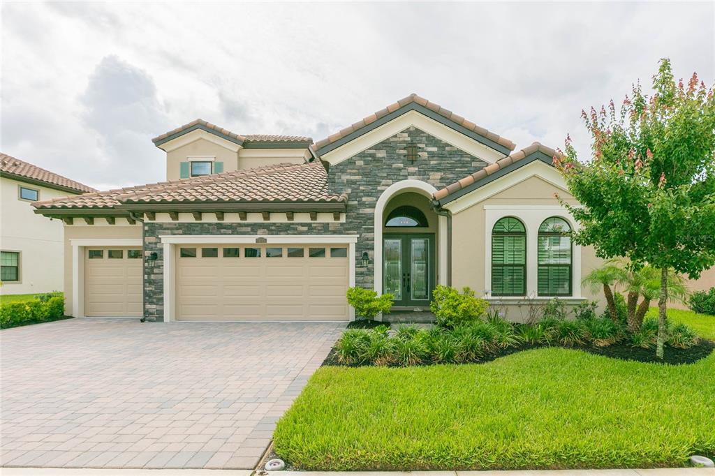 A single-story house with a stone facade, a three-car garage, and a paved driveway — 11105 RUSTIC TIMBER LOOP, SAN ANTONIO, FL