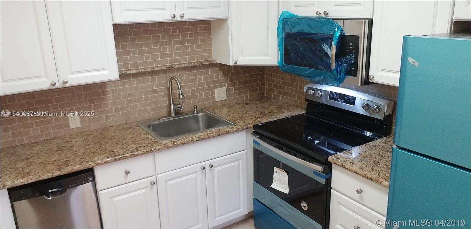 A kitchen features white cabinets, granite countertops, a stainless steel sink, and a black stove — 366 Fanshaw I # 366, Boca Raton FL 33434, BOCA RATON, FL