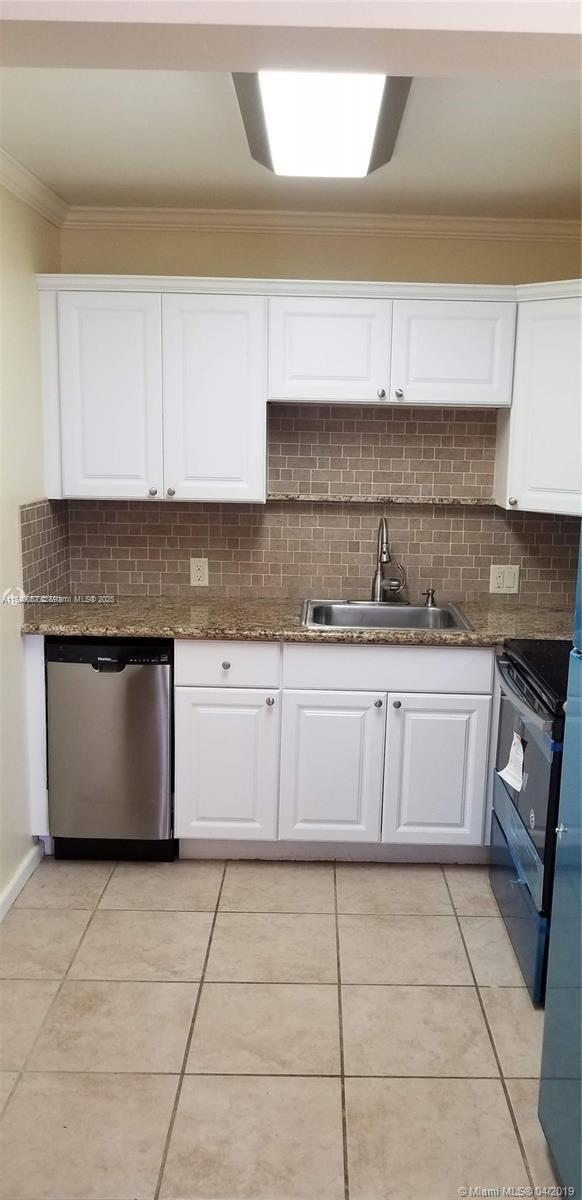 A kitchen features white cabinets, granite countertops, a stainless steel dishwasher, and a tiled backsplash — 366 Fanshaw I # 366, Boca Raton FL 33434, BOCA RATON, FL