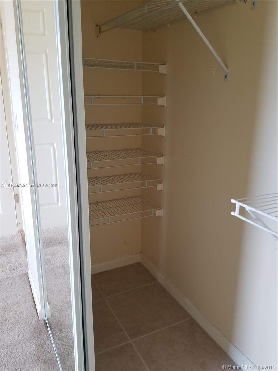 A walk-in closet features white wire shelving units and tiled flooring — 366 Fanshaw I # 366, Boca Raton FL 33434, BOCA RATON, FL