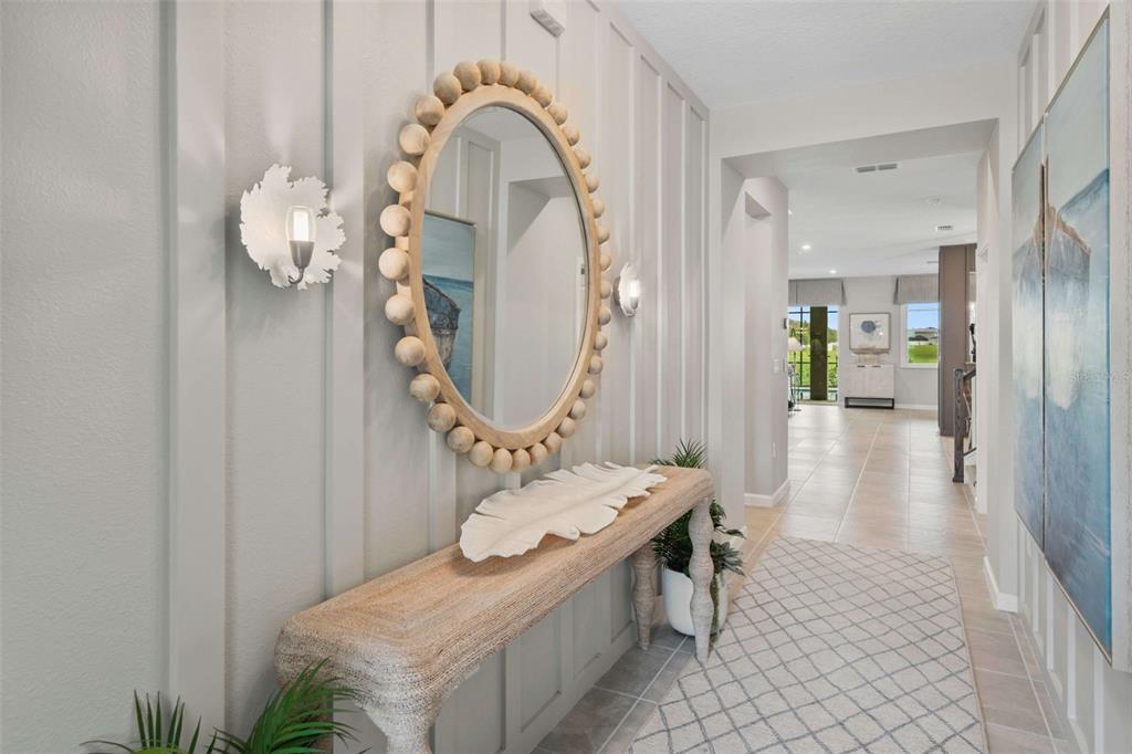 A hallway features a beaded mirror, a console table, and wall sconces on board-and-batten walls — 9127 TURQUOISE WAVE COVE, KISSIMMEE, FL