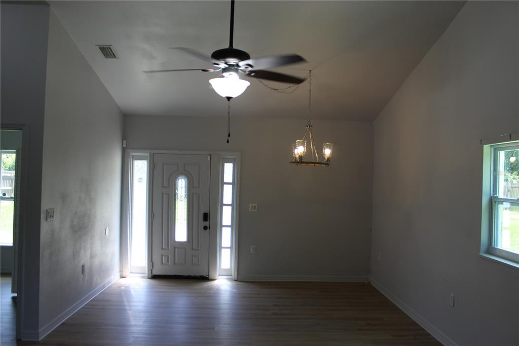 An entryway with light wood flooring, a ceiling fan, a chandelier, and a front door — 11413 PRUETT ROAD, SEFFNER, FL