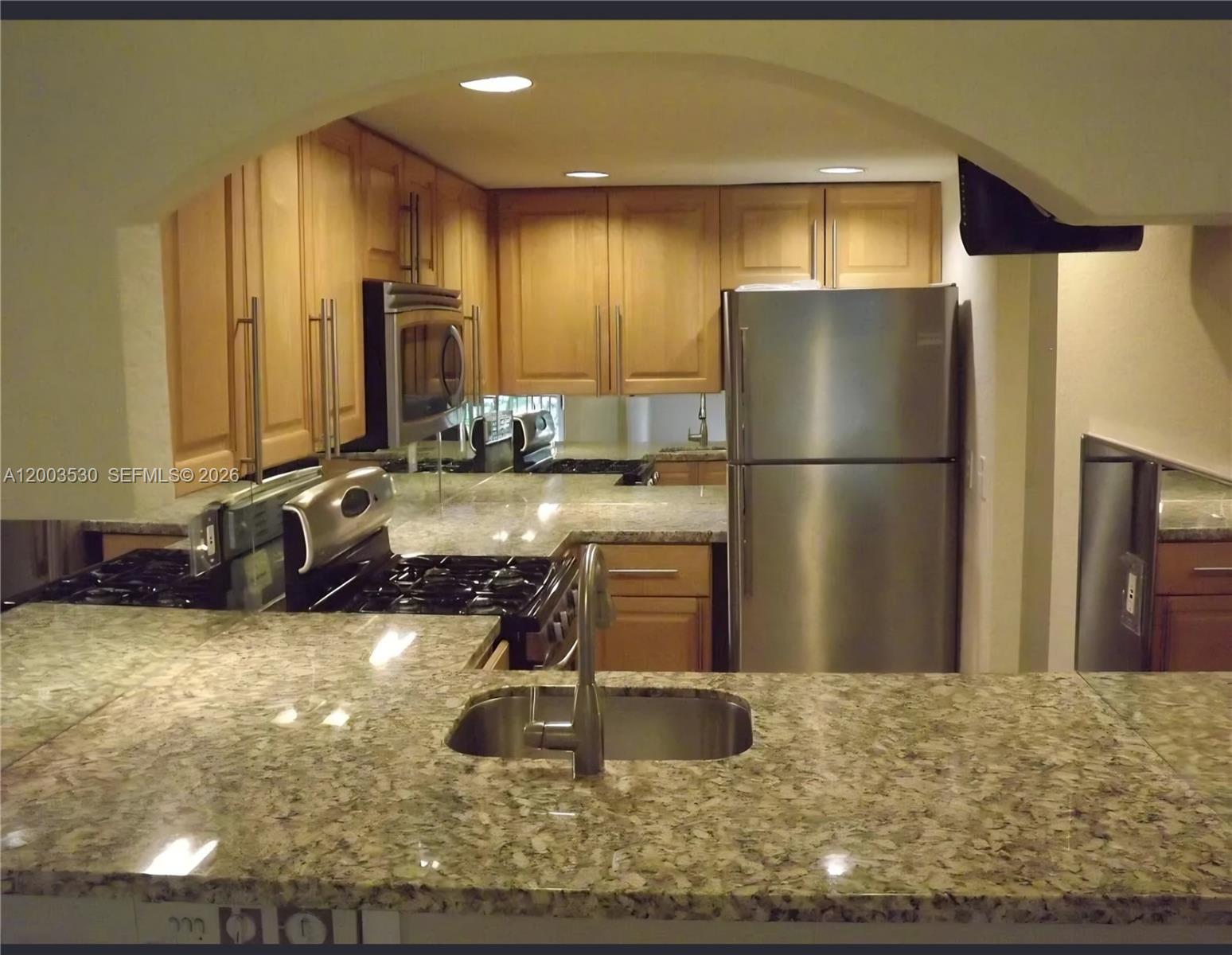 A kitchen features light wood cabinets, granite countertops, and stainless steel appliances — 6709 N Kendall Dr # 228, Pinecrest FL 33156, PINECREST, FL
