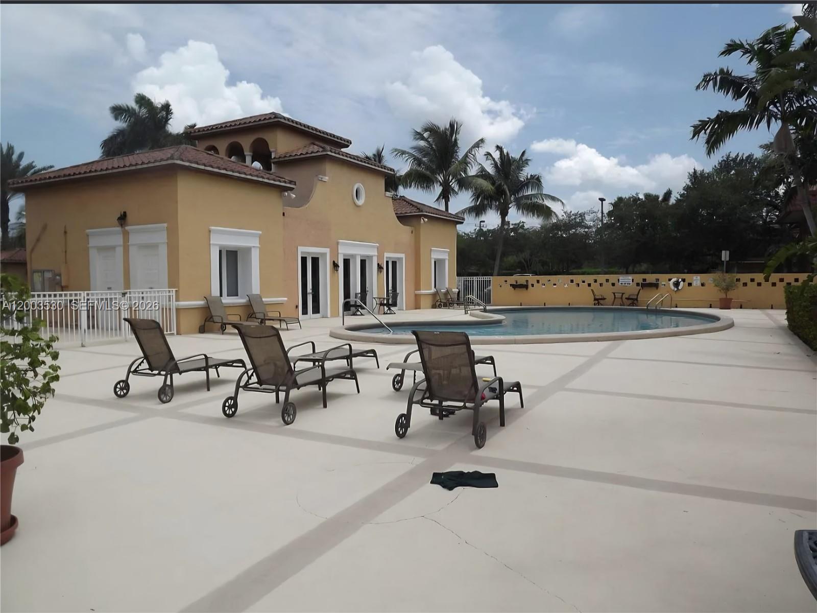A swimming pool area with lounge chairs on a patio in front of a building — 6709 N Kendall Dr # 228, Pinecrest FL 33156, PINECREST, FL