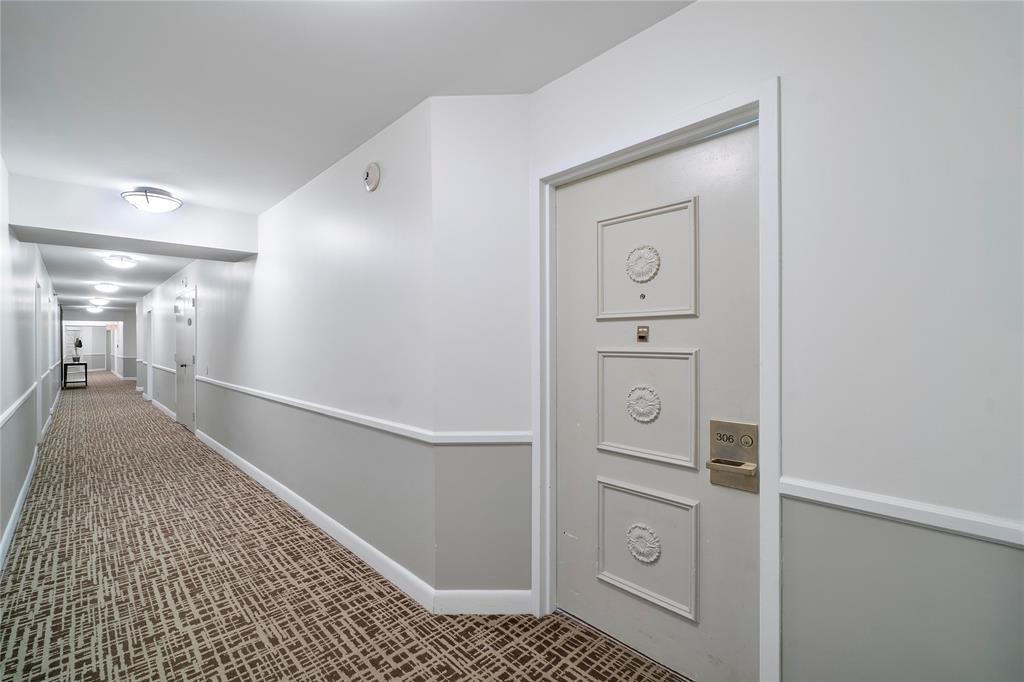 A hallway with patterned carpet leads to a door labeled 306 in a residential building — 300 Three Islands Boulevard # 306, Hallandale Beach FL 33009, HALLANDALE BEACH, FL
