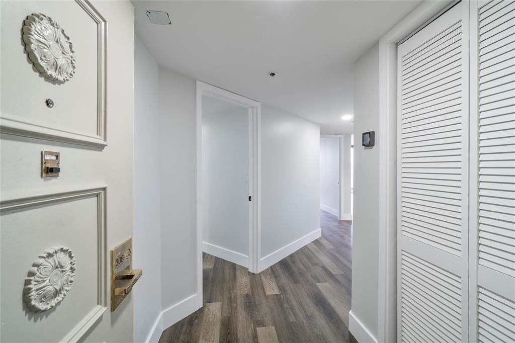 A hallway with wood-look flooring leads to an interior doorway and a louvered closet door — 300 Three Islands Boulevard # 306, Hallandale Beach FL 33009, HALLANDALE BEACH, FL