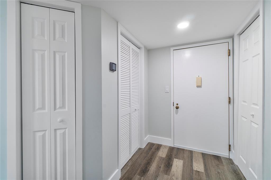 An entryway with wood-look flooring, white walls, and three sets of closet doors — 300 Three Islands Boulevard # 306, Hallandale Beach FL 33009, HALLANDALE BEACH, FL