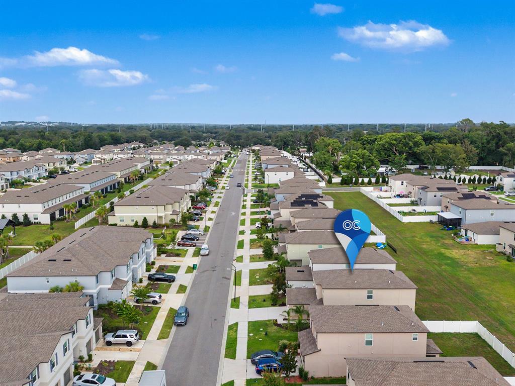 An aerial view shows a suburban neighborhood with rows of townhouses and a street — 36420 GARDEN WALL WAY, ZEPHYRHILLS, FL
