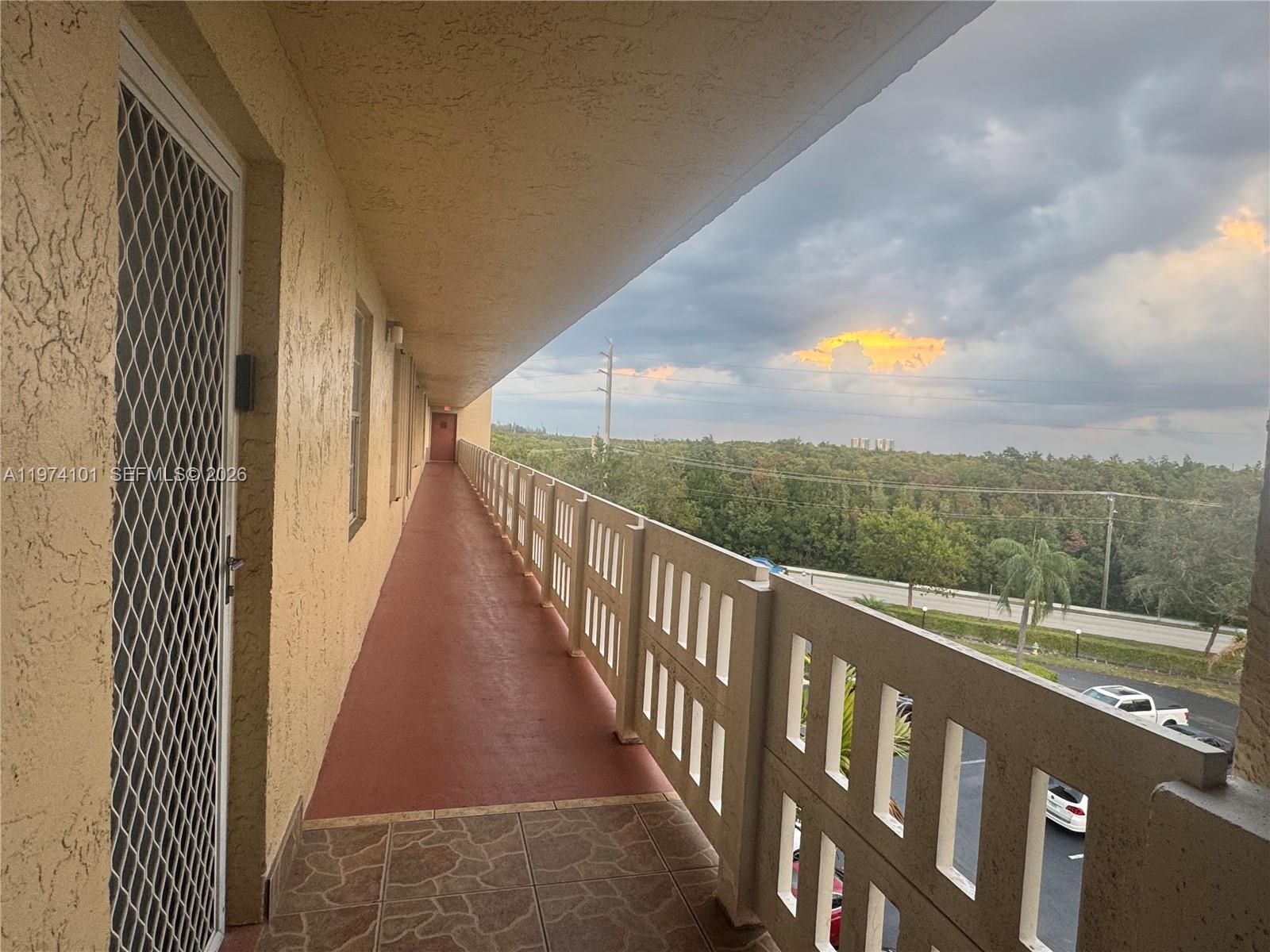 An outdoor apartment balcony features a red floor, a white railing, and a scenic view — 441 SE 3rd St # 505, Dania Beach FL 33004, DANIA BEACH, FL