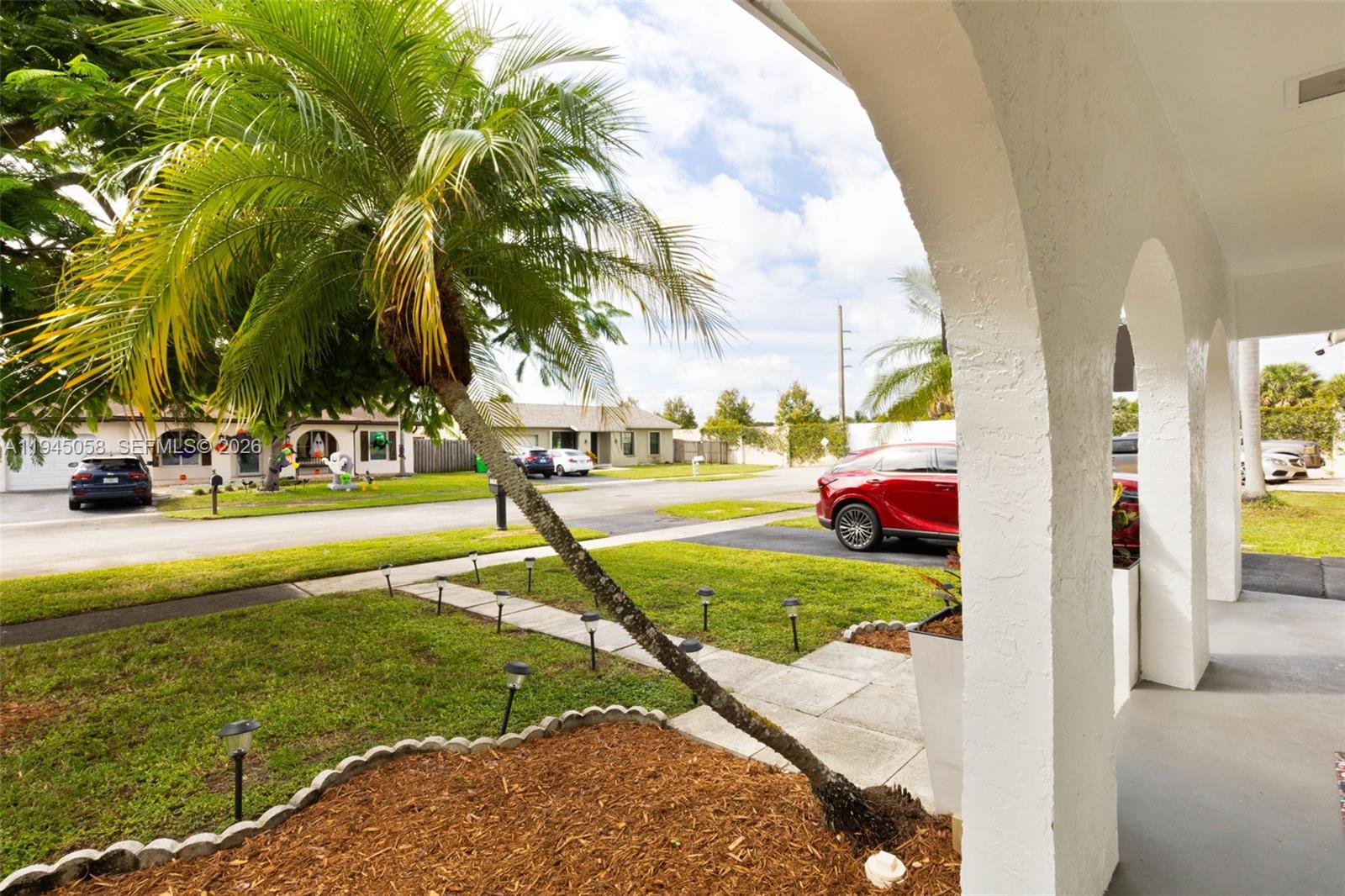 A view from a covered porch looking out toward a suburban street and palm tree — 11145 NW 27th St, Sunrise FL 33322, SUNRISE, FL