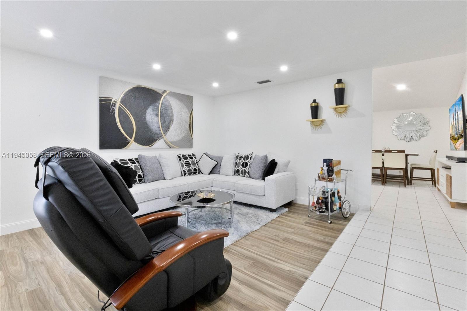 A living room features a sectional sofa, a recliner, and a bar cart on wood-look flooring — 11145 NW 27th St, Sunrise FL 33322, SUNRISE, FL