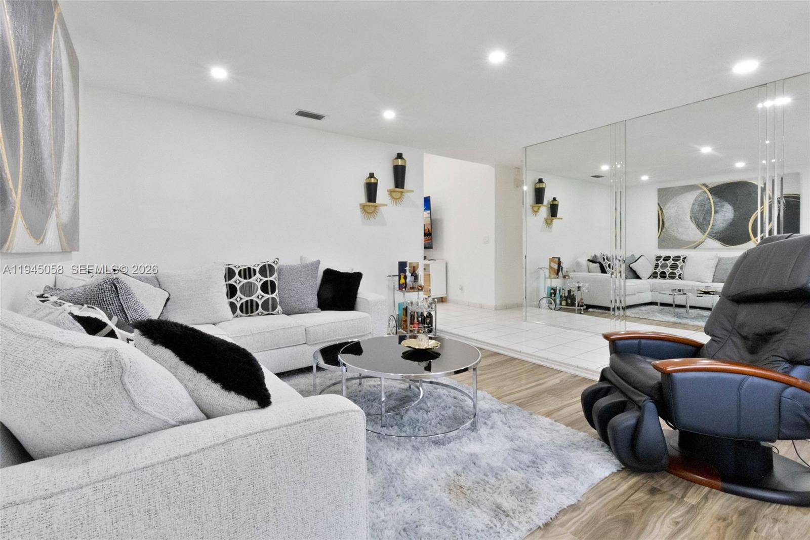 A living room features a white sofa, a black massage chair, and a mirrored wall — 11145 NW 27th St, Sunrise FL 33322, SUNRISE, FL