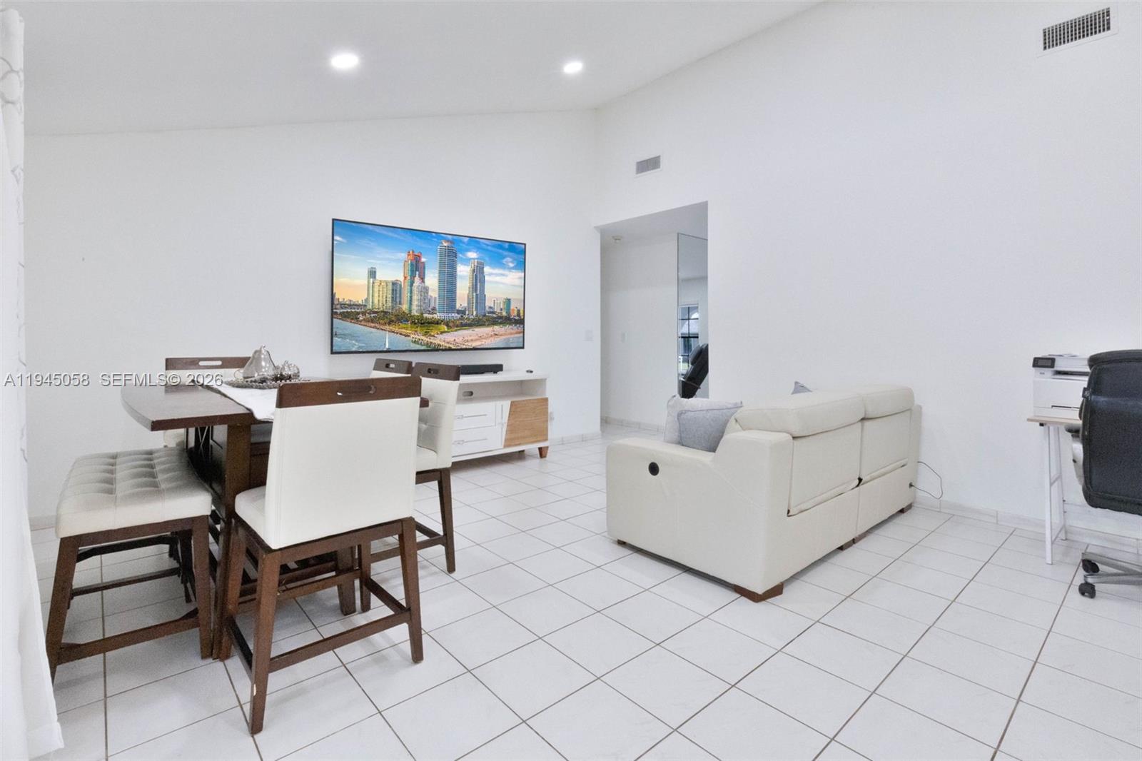 A living and dining area features white tile floors, a wall-mounted television, and white furniture — 11145 NW 27th St, Sunrise FL 33322, SUNRISE, FL