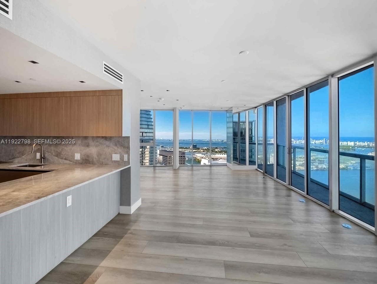 An open-concept kitchen and living area features floor-to-ceiling windows with expansive water views — 465 Brickell Ave # 5701, Miami FL 33131, MIAMI, FL