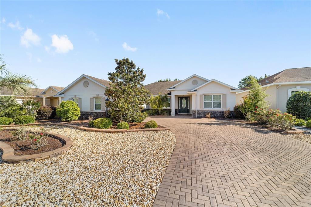 A single-story house with a paved driveway, stone accents, and landscaped front yard — 8889 SW 86TH LOOP, OCALA, FL