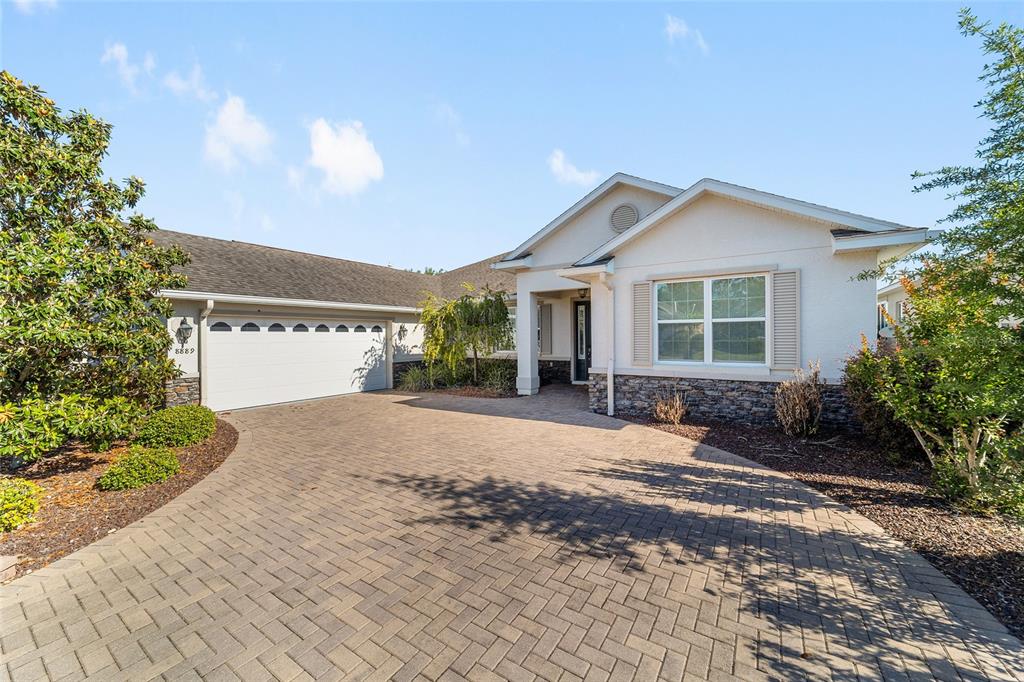A single-story house with a stone facade, white stucco walls, and a paved driveway — 8889 SW 86TH LOOP, OCALA, FL