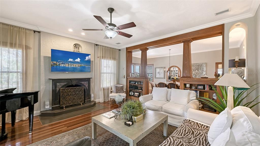 A living room features a fireplace, a ceiling fan, and wooden columns separating the space — 1563 4TH STREET, SARASOTA, FL