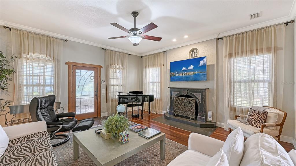 A living room features a fireplace, a grand piano, a ceiling fan, and zebra-patterned furniture — 1563 4TH STREET, SARASOTA, FL