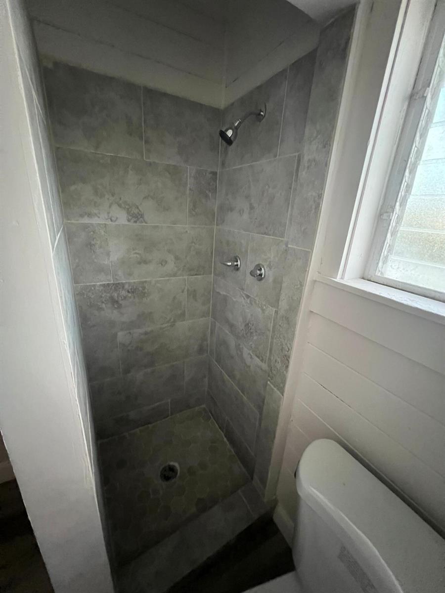 A tiled walk-in shower with a showerhead and controls is located next to a toilet — 2843 Forest Hill Boulevard # 7, West Palm Beach FL 33406, WEST PALM BEACH, FL
