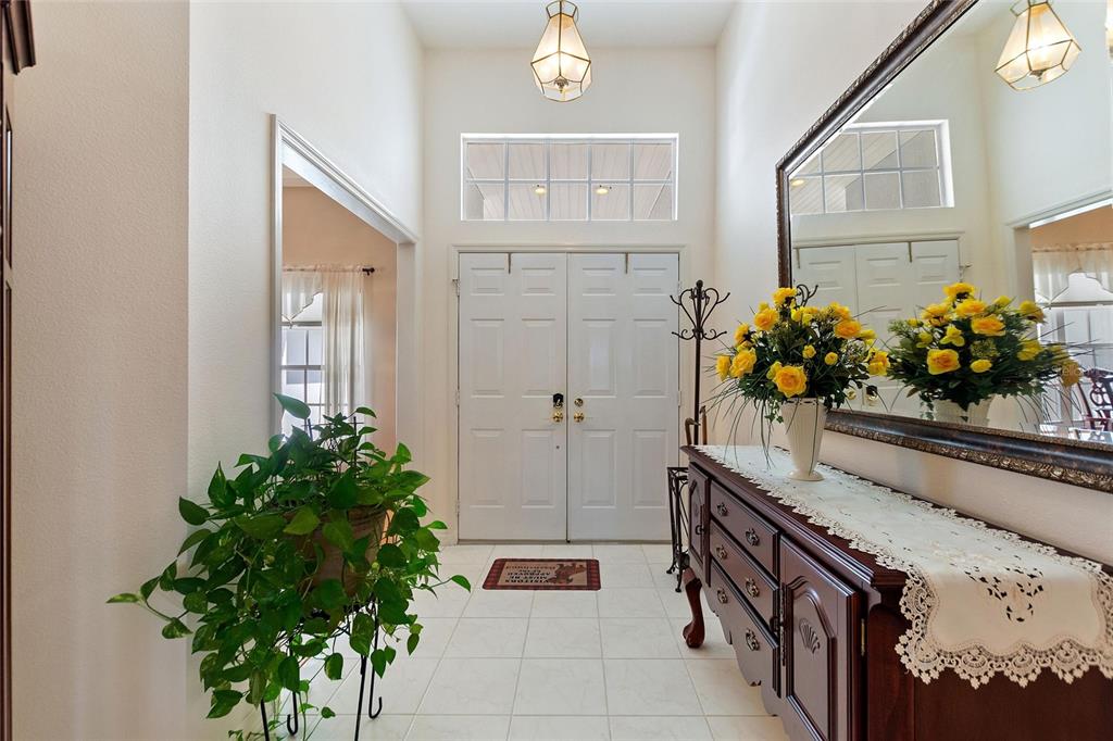 A bright entryway features white double doors, tile flooring, a wooden console table, and mirrors — 5521 EMERALD RIDGE BOULEVARD, LAKELAND, FL