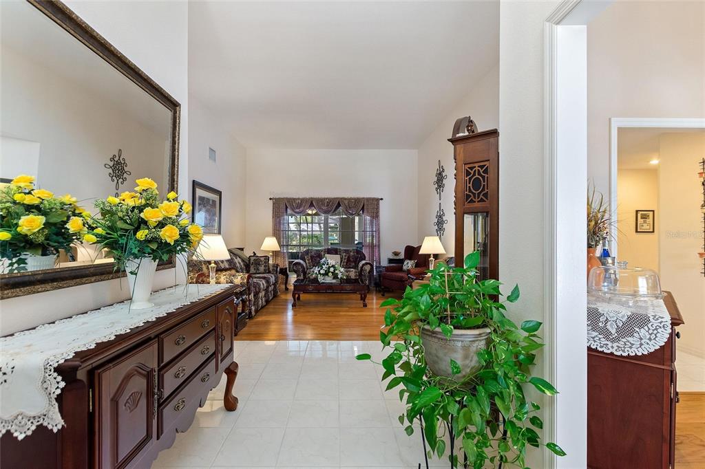 A foyer with a wooden console table leads into a living room with hardwood floors — 5521 EMERALD RIDGE BOULEVARD, LAKELAND, FL