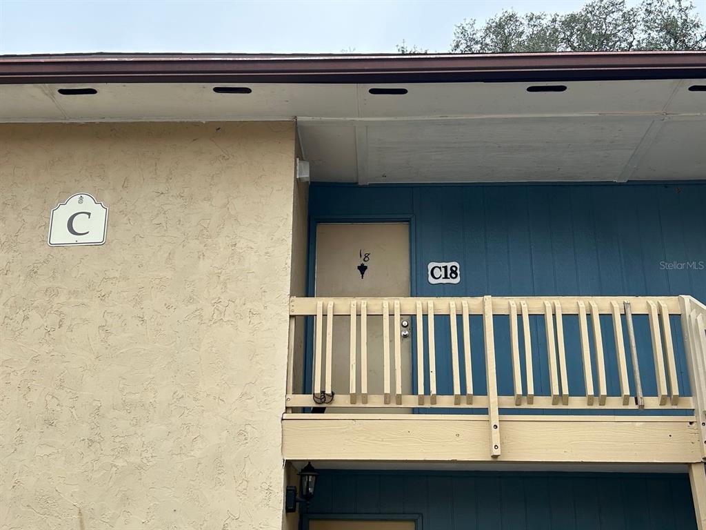 An exterior view shows a tan stucco building with a blue door labeled C18 — 2811 SW ARCHER ROAD UNIT C-18, GAINESVILLE, FL