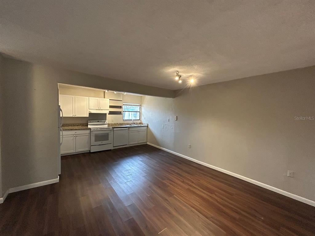An open-concept kitchen with white cabinets and wood-look flooring flows into a living area — 2811 SW ARCHER ROAD UNIT C-18, GAINESVILLE, FL